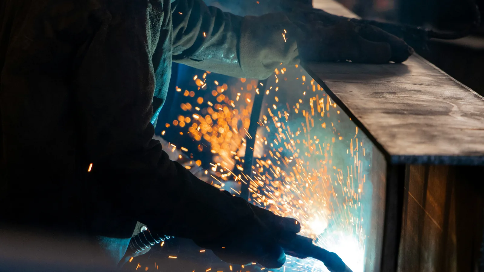Welder fabricating steel with sparks flying
